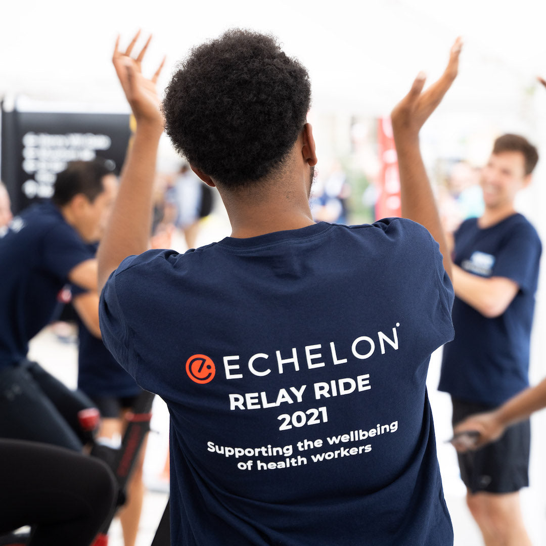 NHS x Echelon Charity event to support St Barts, man raises hands to clap in event t-shirt